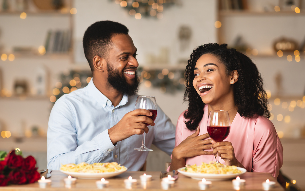 Happy black woman and man drinking wine and laughing
